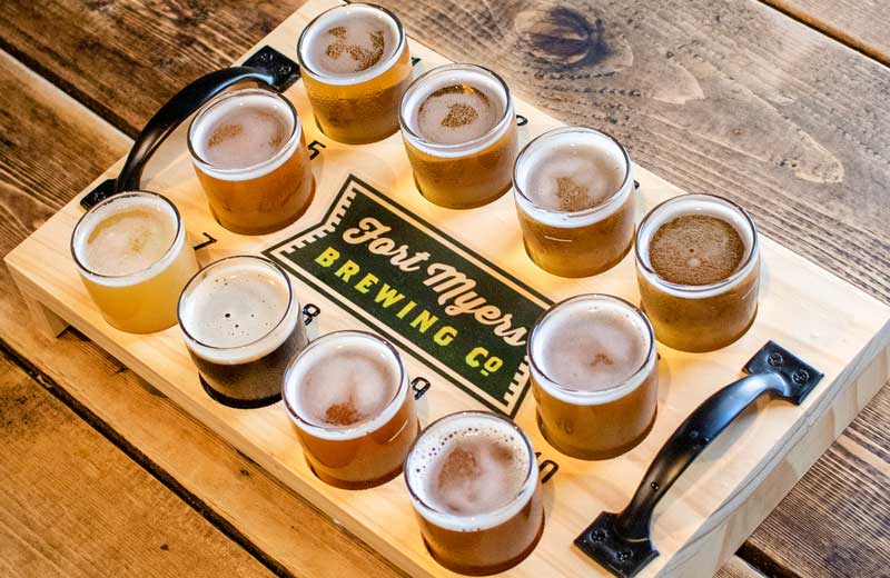 A tray of beers on a wooden table.