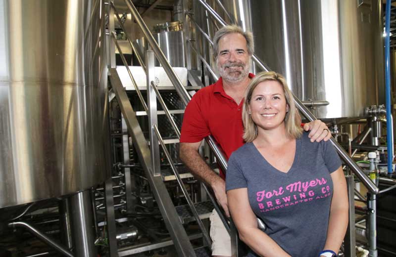 A man and woman standing in front of a brewery.