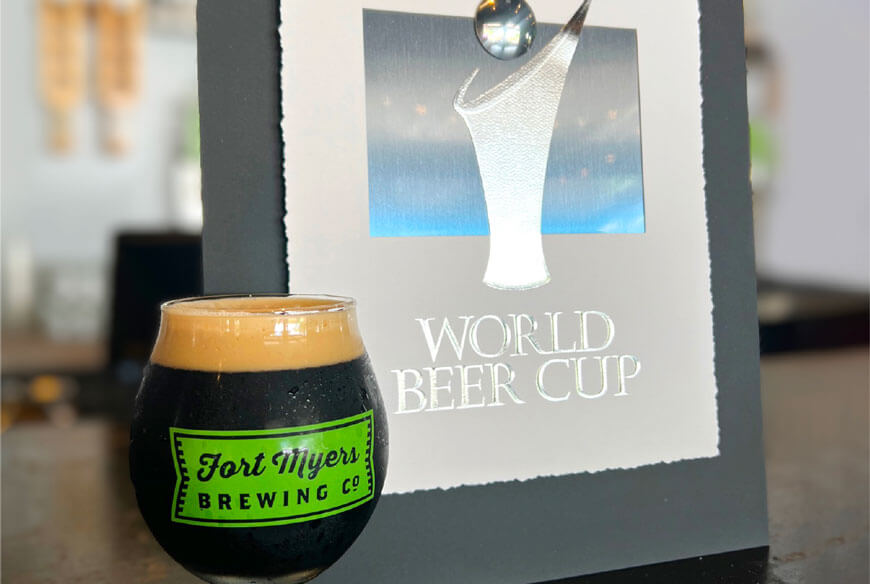 A glass of beer next to a sign that says world beer cup.