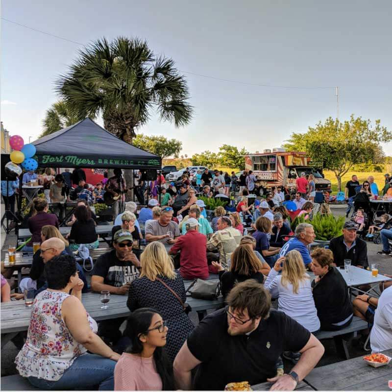 a crowd of people sitting at tables at an outdoor event.