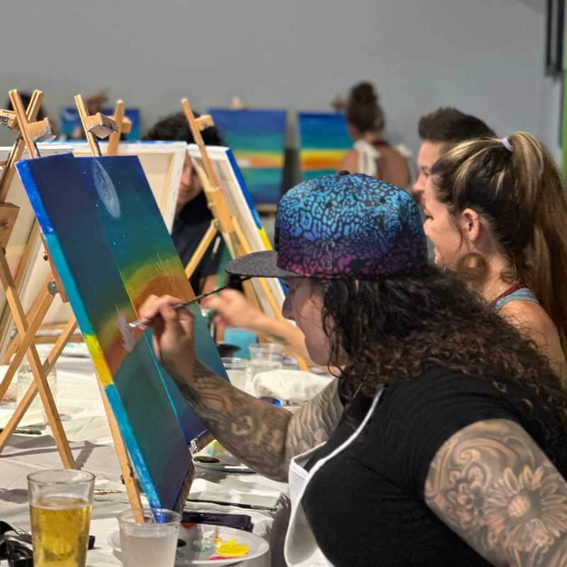 a group of people painting on easels at an event.